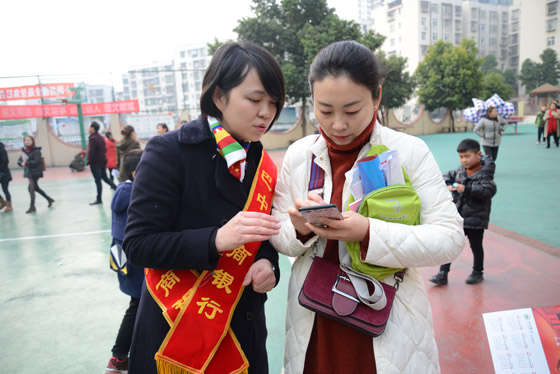 2 巴中農(nóng)商銀行經(jīng)開區(qū)支行工作人員指導(dǎo)家長正確使用手機(jī)銀行.jpg