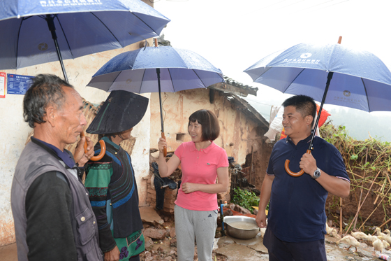 西昌金信村鎮(zhèn)銀行黨支部書記、董事長梁文英冒雨深入貧困戶家中了解情況.JPG