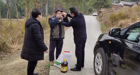 圖為劉陽德書記向幫扶戶付運(yùn)才送防疫物資并親自教其戴口罩.png