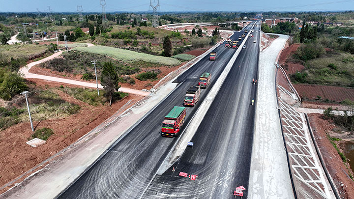 1681724408531110.jpg 1內(nèi)大高速公路(四川境)項(xiàng)目施工現(xiàn)場(chǎng),筑路工人在東興樞紐互通區(qū)域鋪筑瀝青混凝土路面(無(wú)人機(jī)照片).jpg