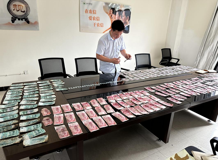 2張場支行組織工作人員在會議室清理晾曬浸濕紙幣.png