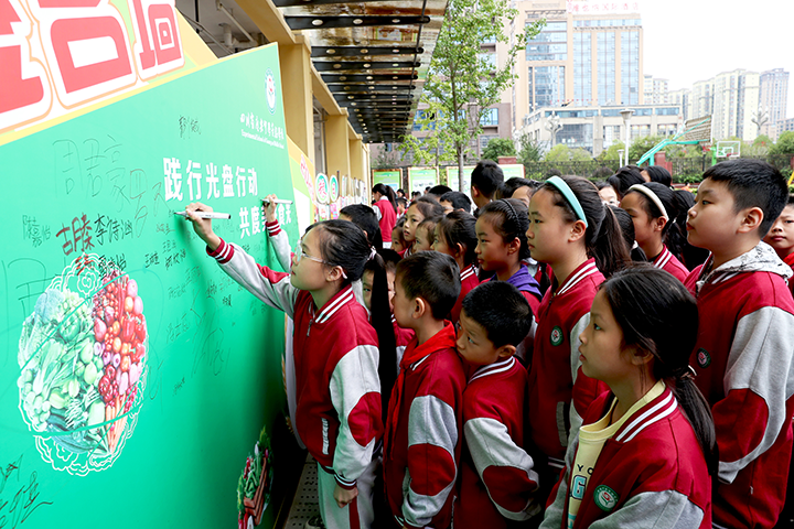 圖3  10月12日，四川省廣安市廣安區(qū)廣安中學(xué)實驗學(xué)校營養(yǎng)餐食堂門口，該校學(xué)生正在簽名承諾：光盤行動，從我做起。.png