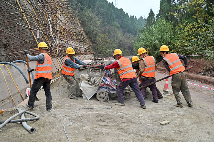 圖2  筑路工人在內(nèi)吳路項(xiàng)目施工現(xiàn)場(chǎng)搬移拌料設(shè)備.jpg