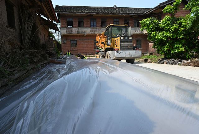 圖5  4月15日，內江市東興區(qū)椑木鎮(zhèn)新田社區(qū)10組，建設者對硬化院壩進行覆膜保養(yǎng)。.jpg