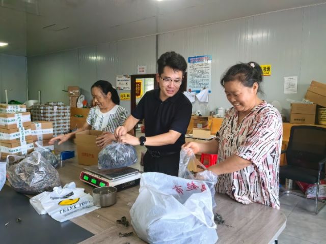 圖3  關(guān)祖蘋正在和村電商中心工人一起稱重打包“土貨”。潘政吉  攝.jpg