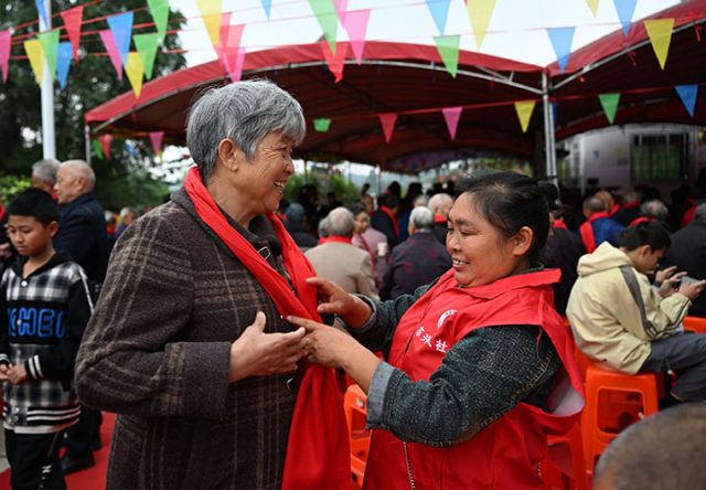 圖1  10月25日，四川省內(nèi)江市東興區(qū)永福鎮(zhèn)鯉魚塘村，志愿者為村里的老人系上暖心的紅圍巾。.jpg
