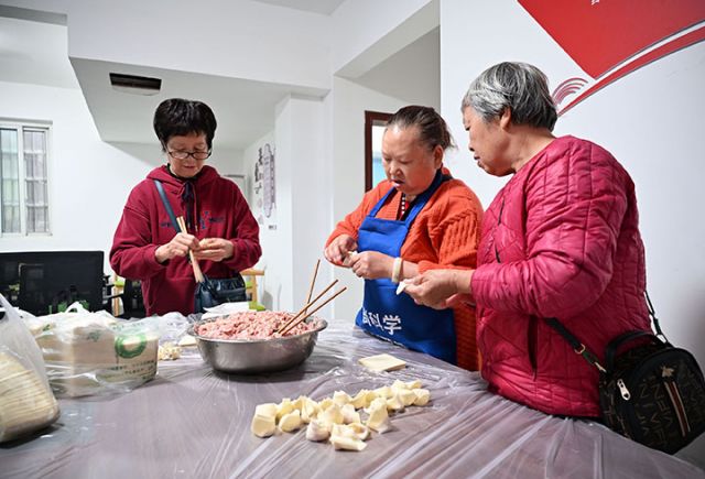 圖3  志愿者與老人一起包抄手.jpg